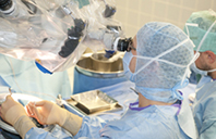 Operativer Eingriff in der Neurochirurgie, zwei Personen in Operations-Kleidung arbeiten, der Chirurg operiert mit einer Mikroskop-Kamera